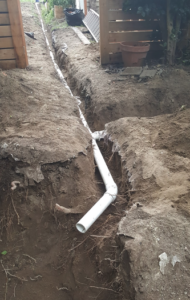 A long, straight trench with PVC pipe inserted. 